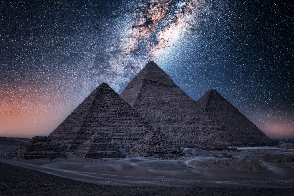 This image shows the Great Pyramids of Giza in the foreground, with the Milky Way in the sky above. The construction of these monumental structures marked an important milestone in the history of land surveying.