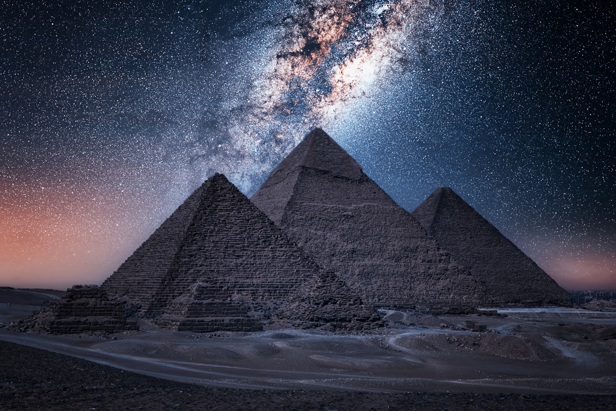 This image shows the Great Pyramids of Giza in the foreground with the Milky Way in the sky above them. The construction of these monumental structures marked an important accomplishment in the history of land surveying.